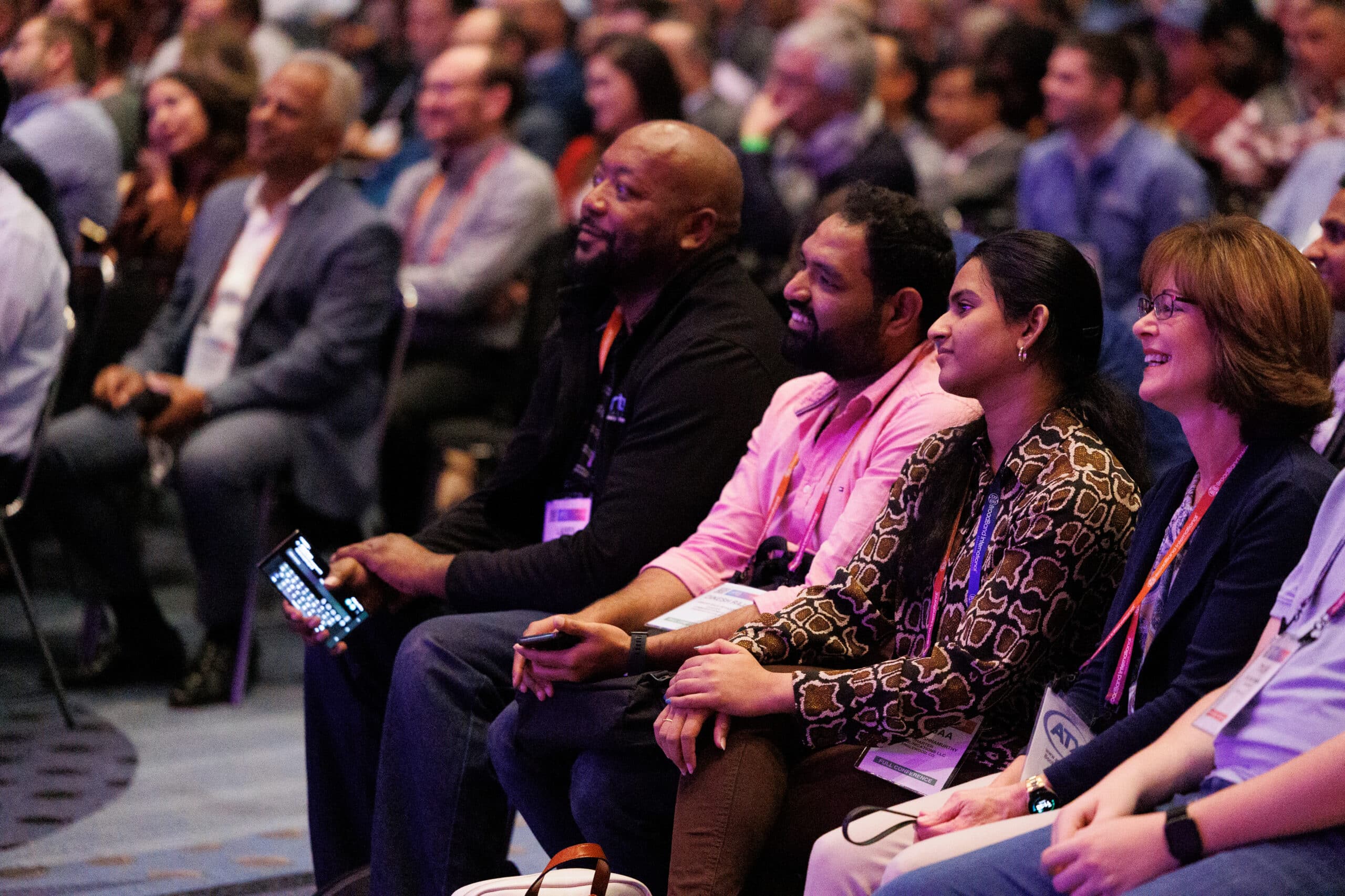 Audience members at a conference looking at the stage and smiling