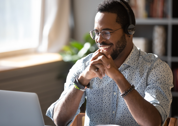 Person smiling looking at their laptop with headphones on